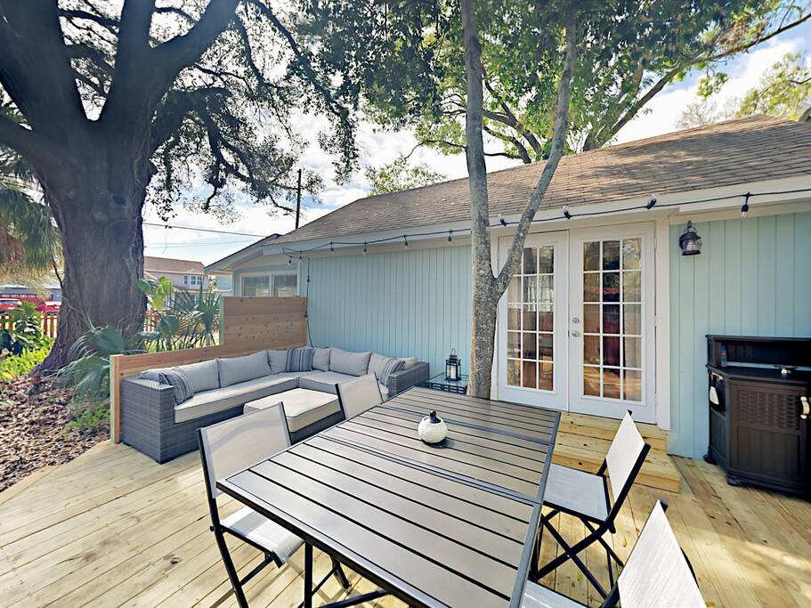 Main deck with gas grill, open-air dining for 4, and a sectional wicker sofa.