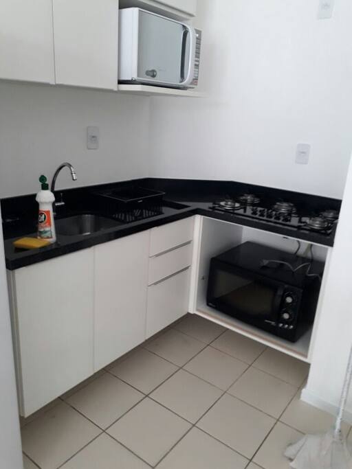 Cozinha com pia, fogão, forno elétrico, geladeira e microondas