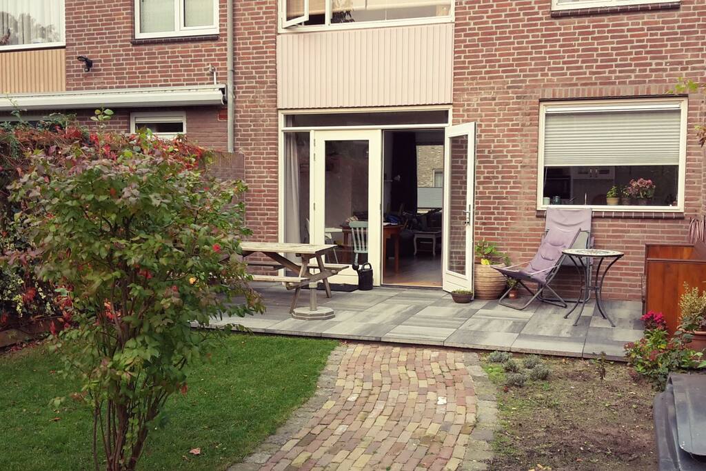 Achtertuin op het zuiden met groot terras, groen en opslag.