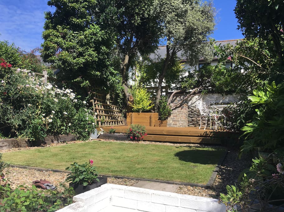 Very sheltered, sunny garden with steps up to a small lawn and wooden deck. Dine outside on the raised deck furnished with a gas BBQ, round metal table and four chairs. A small shed by the kitchen door has a rotary airer and a folding sun lounger.