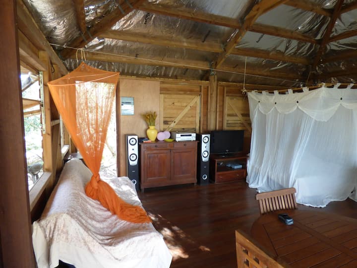 La cama king size debajo de la mosquitera y un sofá cama en el bungalow principal