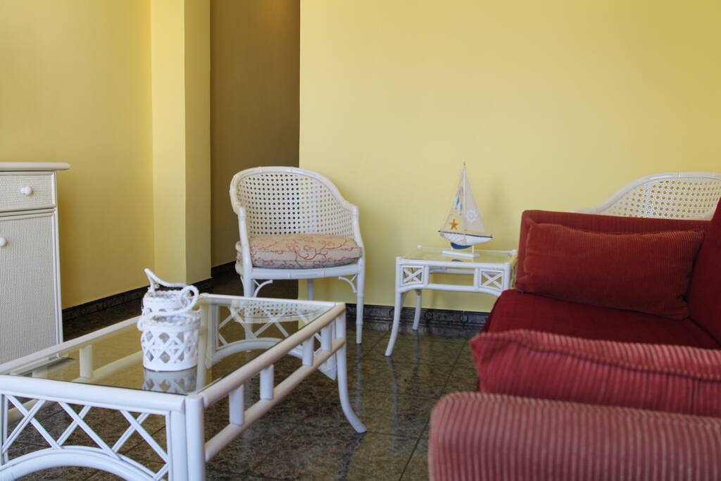 Salon con sofa-cama, mesa de centro y una mesita adicional lateral y dos dos sillas.