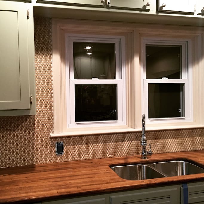Updated kitchen with butcherblock countertops, custom built-ins, Slate GE appliances & Penny Backsplash.