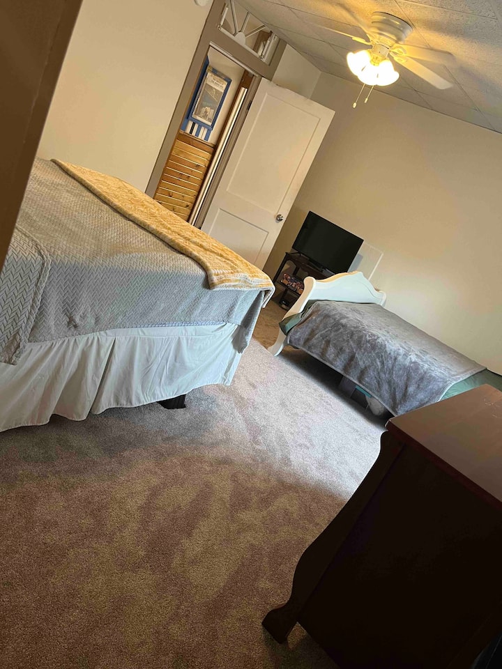 صورة لغرفة النوم تطل على الخارج من مدخل الخزانة. يتم تضمين العديد من أسلاك التمديد وشرائط الطاقة مع كل غرفة للراحة. بالإضافة إلى مروحة السقف في كل غرفة، يتم أيضًا تضمين مروحة صندوقية. 