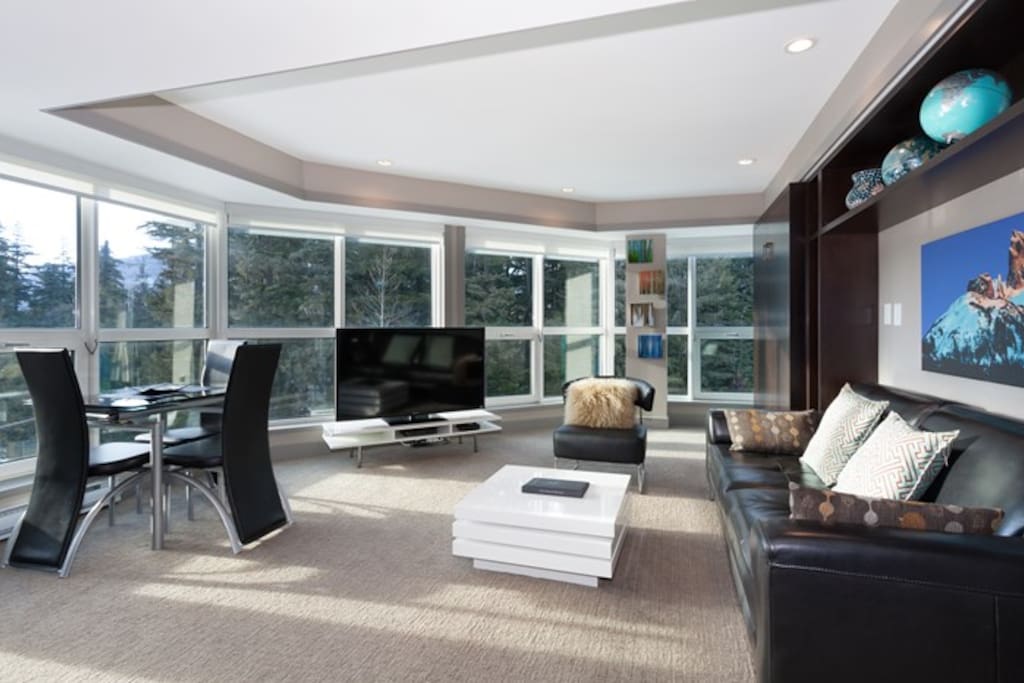 The spacious living area includes a TV, dining table and incredible mountain views.
