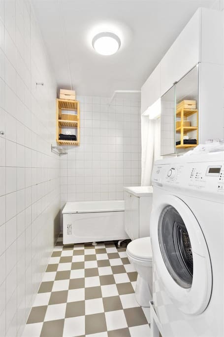 Bathroom with washer and bathtub with shower.