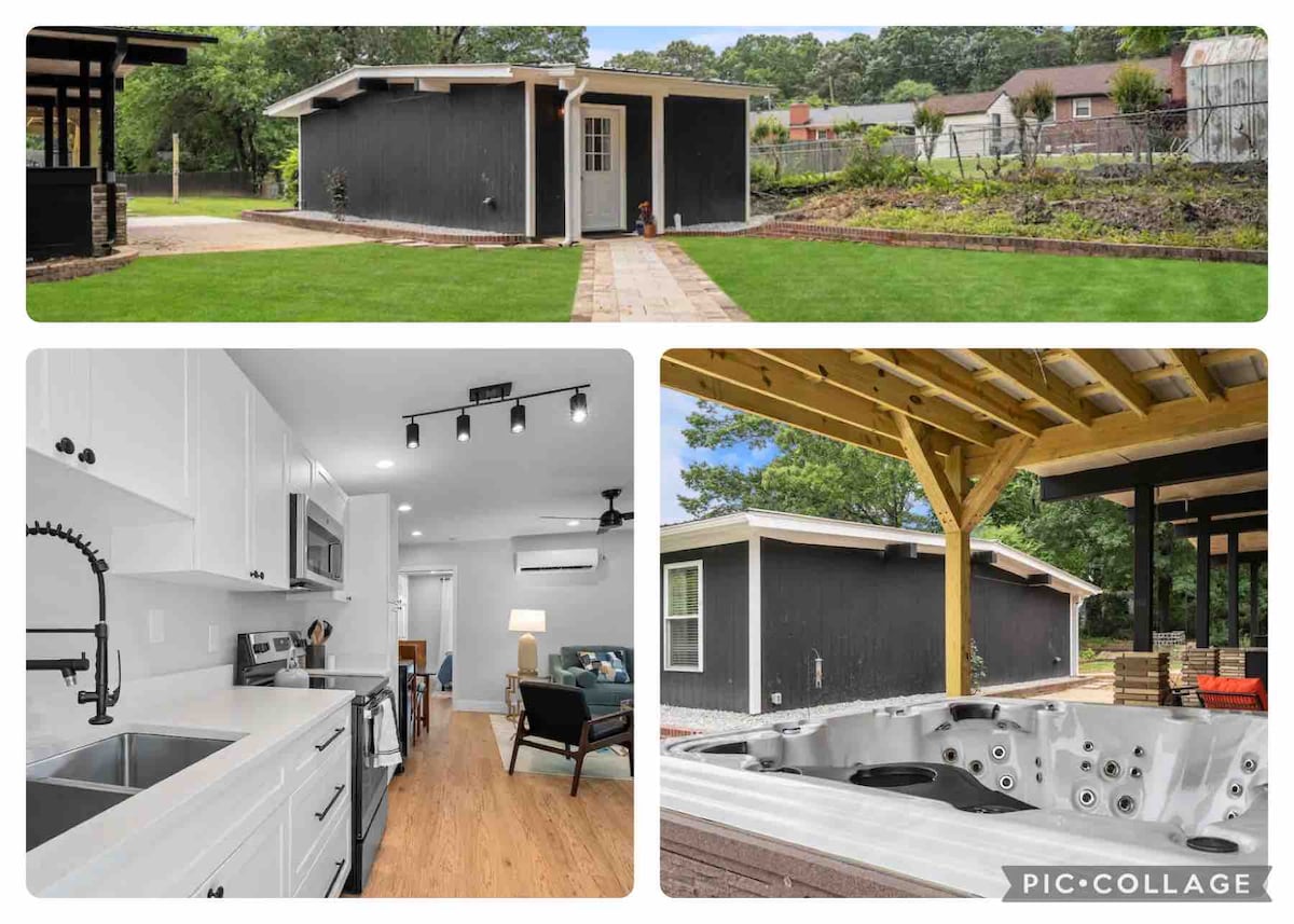 A charming cottage is set on a well-maintained lawn, with a pathway leading to its entry. Flanking greenery enhances the inviting ambiance, while the exterior features a sleek black finish complemented by light-colored door and window trim.