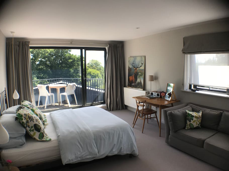 Spacious main bedroom with sofa, desk or dressing table, and own balcony