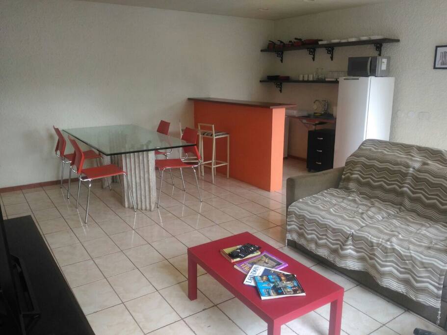 Espaço amplo com cozinha americana completa e grande mesa de jantar