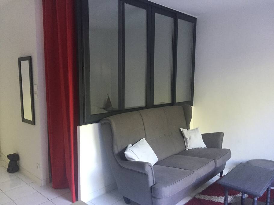 Coin salon avec verrière de séparation avec la chambre.