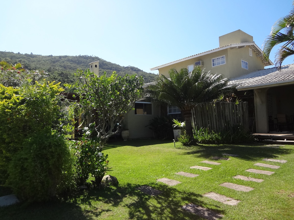 A well-maintained garden is displayed, featuring lush greenery and a variety of plants. The property includes a two-story structure with a light-colored exterior. A pathway made of stepping stones leads through the manicured lawn, inviting a sense of tranquility and nature.