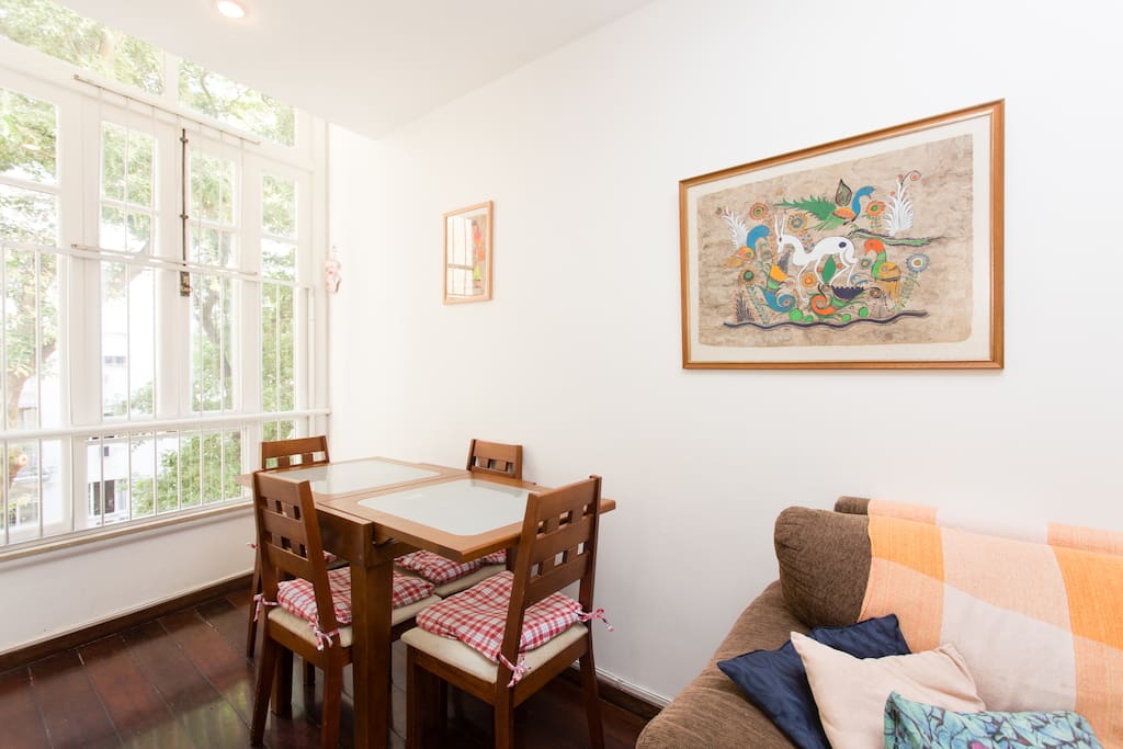 Sala com mesa e vista arborizada.