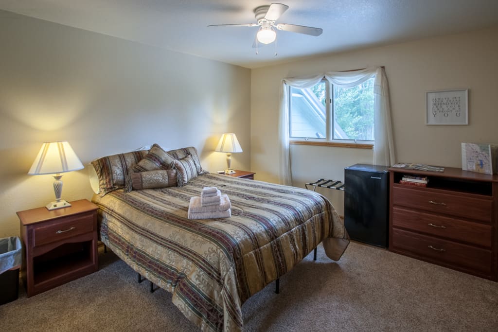 Your bedroom with a new, comfy, queen sized Alexander Signature Series mattress by Nest Bedding, mini fridge and ceiling fan.