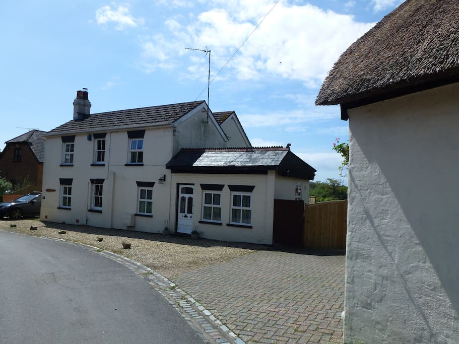 Parking between the house and the thatched garage.