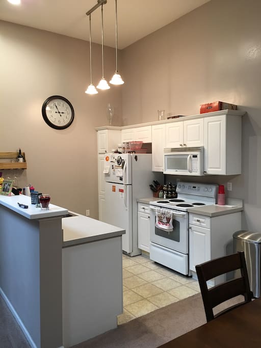 Kitchen with vaulted ceilings. Electric stove and oven microwave fridge sink and dishwasher.