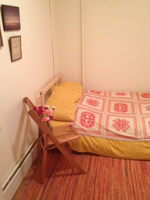 Cozy room. There is twin sized bed, a rack to hang clothes, and a small table and chair.