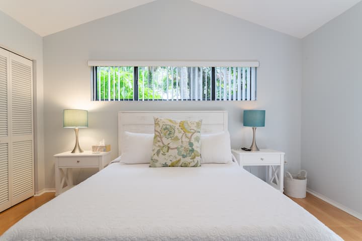 חדר שינה שני עם מיטת קווין סייז ונוף יפהפה של הגינה מעל הראש.