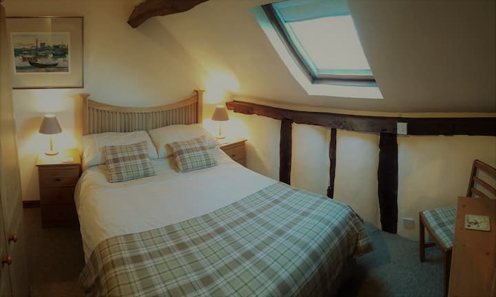Jinney Ring's character double bedroom with exposed beams and large velux window with views over countryside.