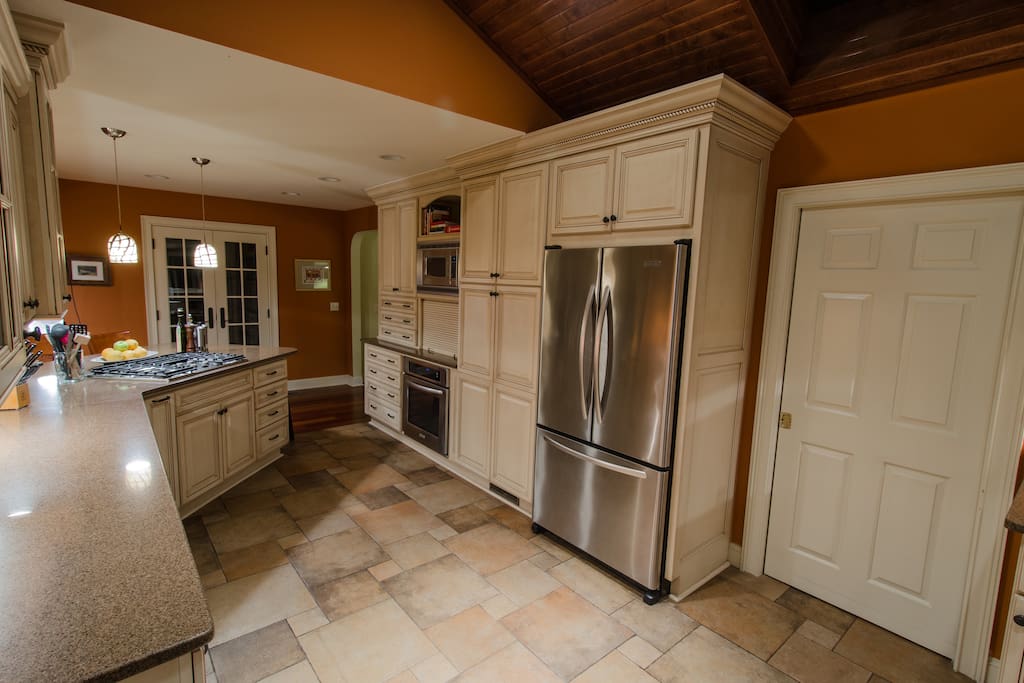 A large kitchen with stainless appliances and tile floor, lead the war to a full size laundry room with a washer and a dryer.