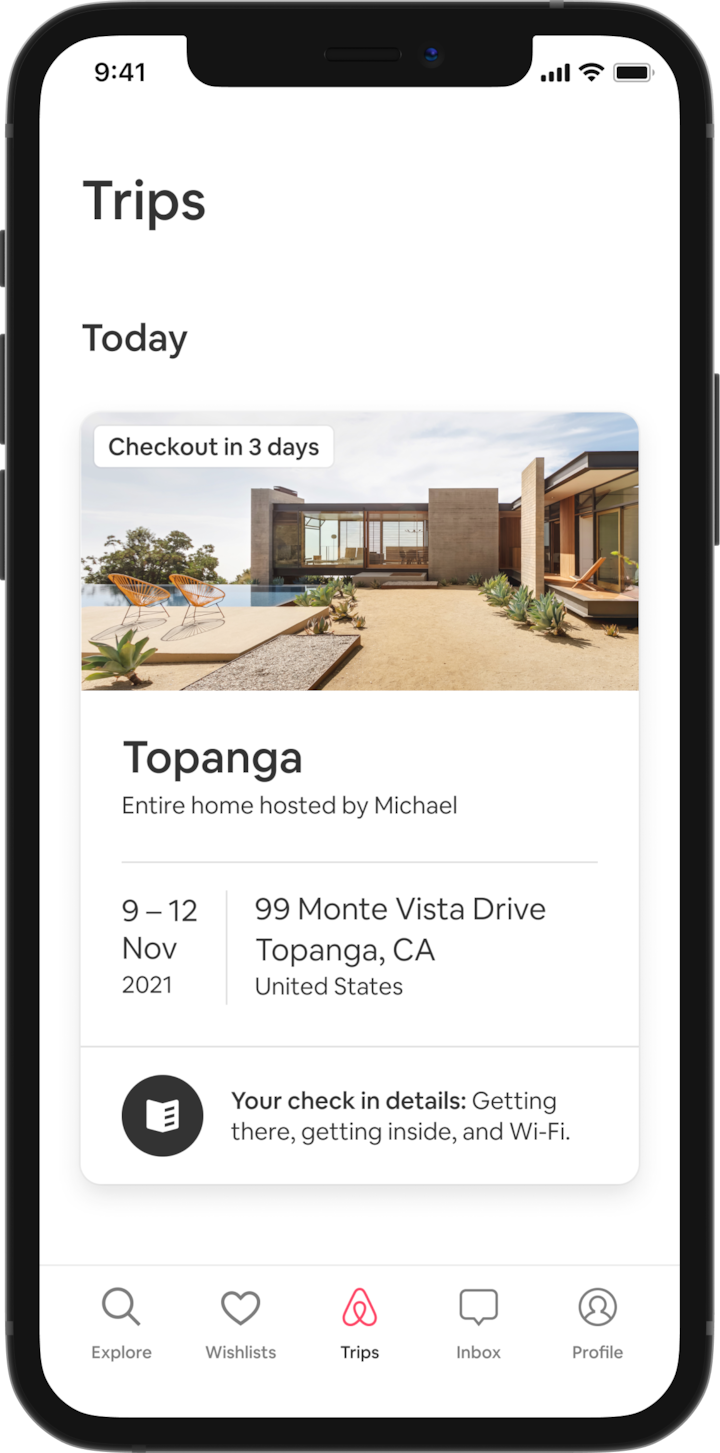 A mobile phone features a guest’s Trip tab which shows an upcoming trip. Under a heading that reads ‘Today’ there is an image of an A-frame house, and under this, there are details about the guest’s booking—the listing name, the names of the Host, the address, and the dates for the trip. At the bottom of the screen there is a button that reads: 'Your check-in details. Getting there, getting inside and Wi-Fi.'