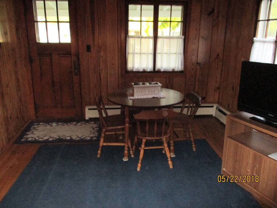 The front area of the cottage has a table and chairs for dining or games.