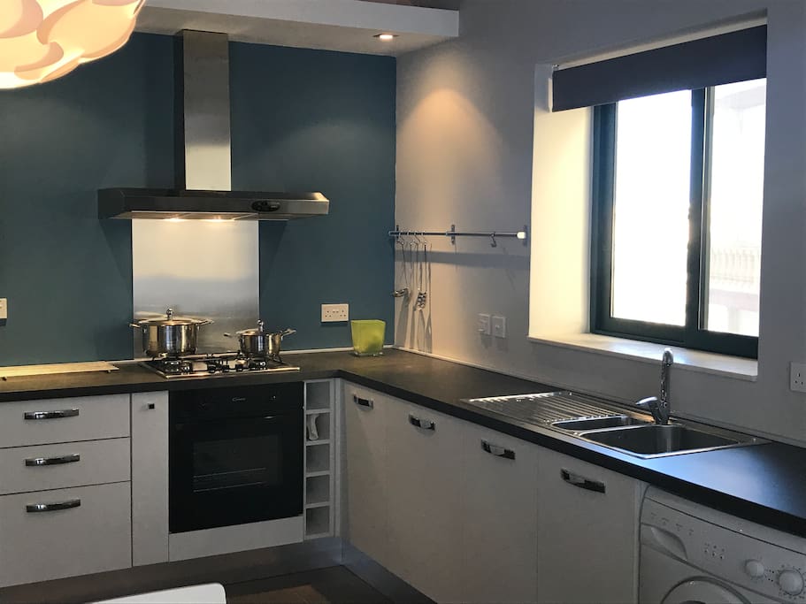 Kitchen with fridge/freezer, electric oven, gas cooktop dishwasher and washing machine.