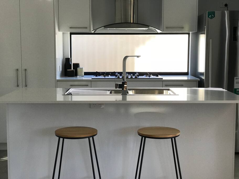 Kitchen equiped with utensils, can opener, knives set, chopping board, wine cork screw, plates, cups, wine glasses, kettle, microwave, non stick pan and pot.