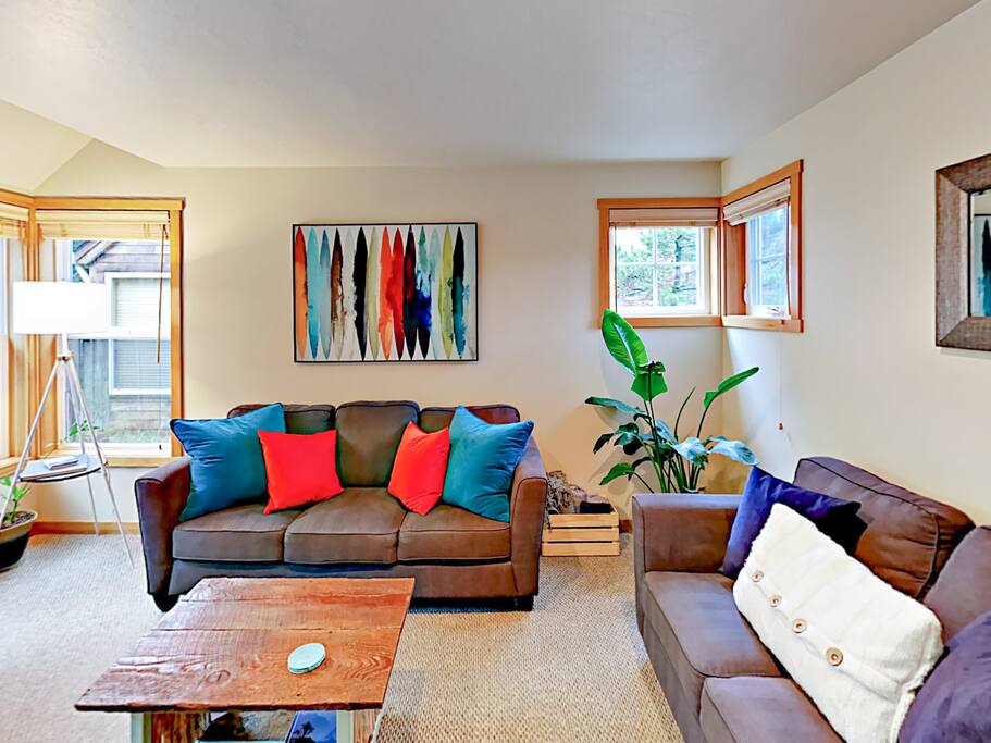 The sun-lit living room includes 2 comfortable sofas.