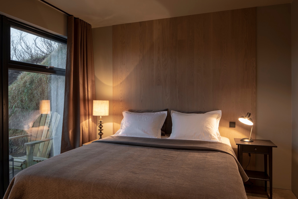 Dormitorio con una cama Jensen de lujo de primera calidad.   Un vestidor y una puerta de salida al patio.