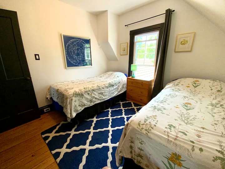 Tercer dormitorio con dos camas individuales, un armario y una silla acogedora.