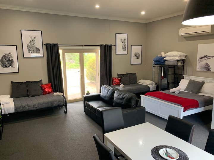 Habitación con capacidad para 6 personas. Cama doble, sofá cama extraíble y dos camas individuales, todo en una habitación abierta.