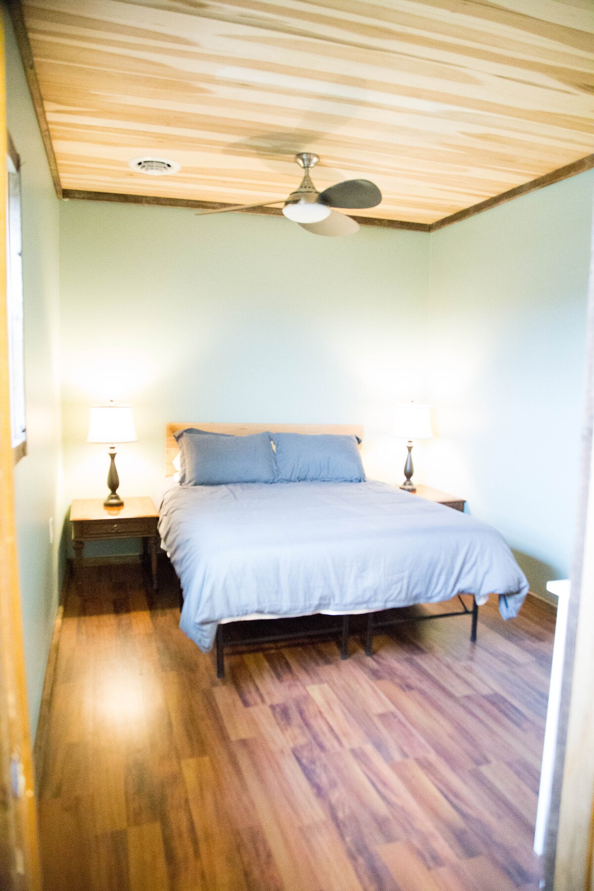 Chambre principale, avec lit queen, grande commode, tables de chevet et ventilateur.