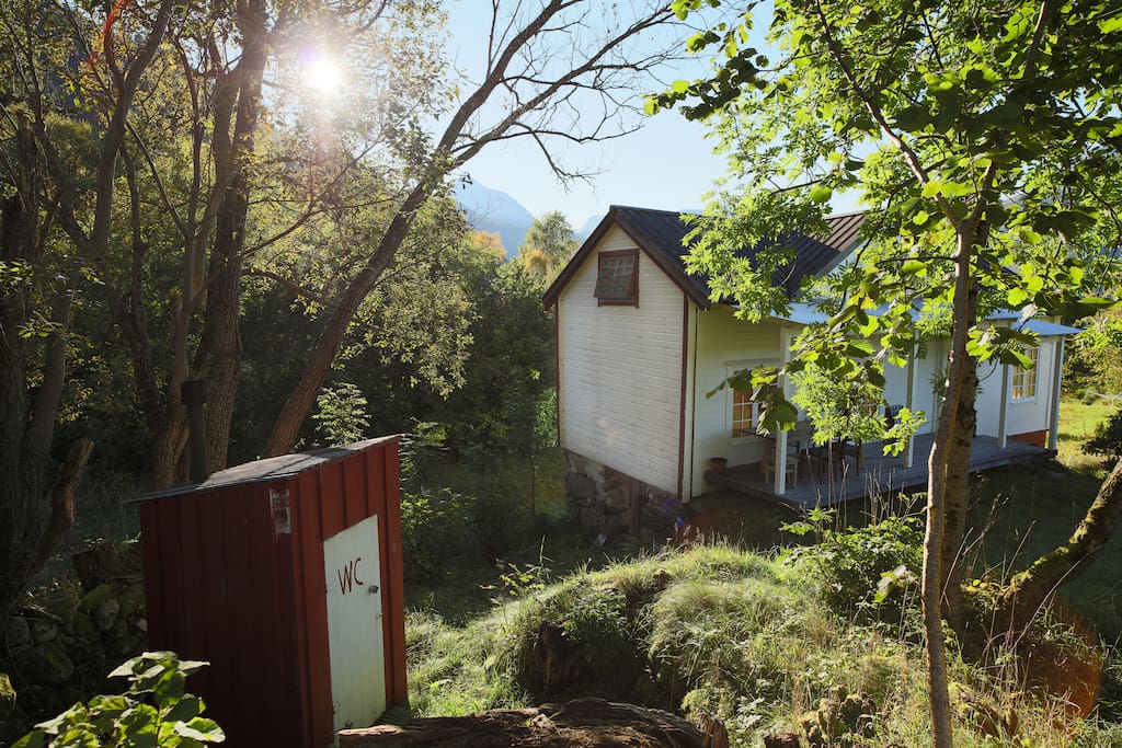 Traditional outhouse and practical porch with afternoon sun.
