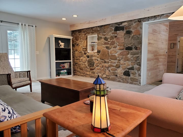 Spacious living room with cobblestone wall, smart Roku-enabled TV with DVD player, books, games,  French doors to patio, comfy couches and an amazing view towards Mullett Lake.