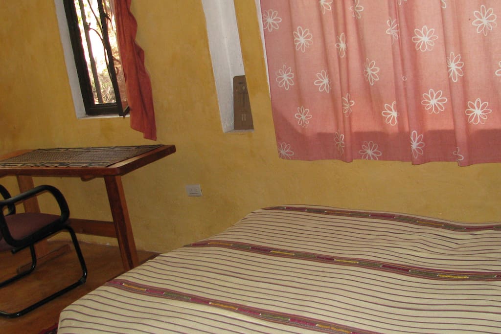 Cama matrimonial junto a las ventanas que dan al estacionamiento