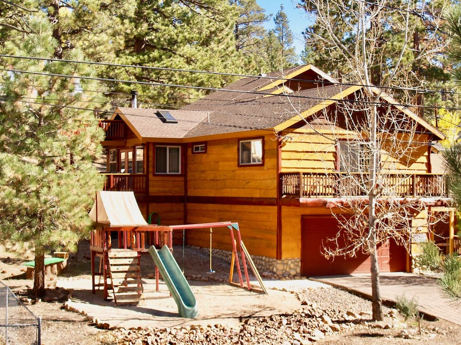 Play ground with swings, slide, and a fort with a climbing wall.