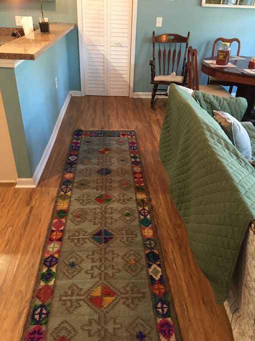 From the front door, view of the hallway that separates living and dining areas from kitchen and bar areas. At the end of the hall is the laundry room complete with washer/dryer, iron and ironing board.