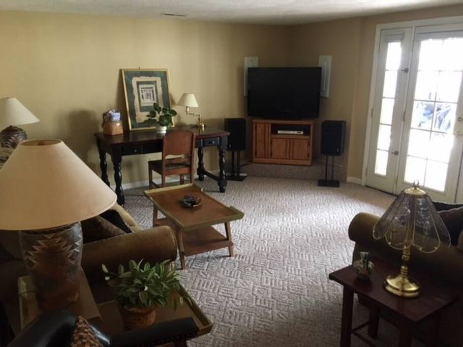 Lower level living room w/ couch, love seat, desk, flat screen TV w/ satellite and DVR/VHS, french doors to patio