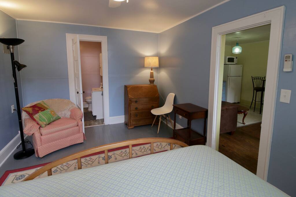 View from bed to desk and reading area. Bathroom entrance.