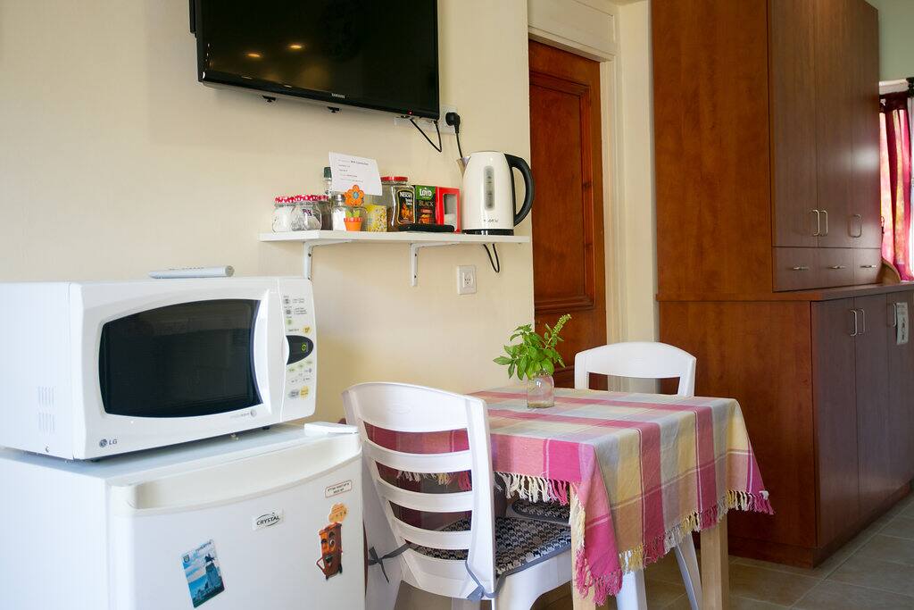 Refrigerator, microwave, electric kettle, dining table and television.