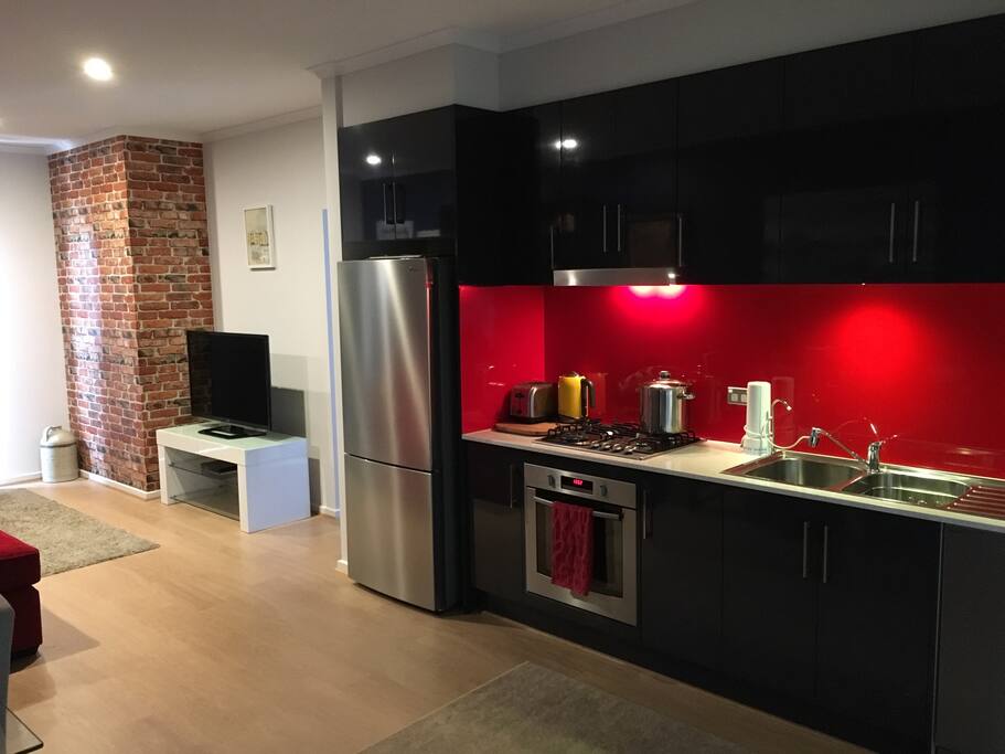 Modern galley kitchen with appliances, cutlery, cooking utensils and condiments. Fridge and cupboard is stocked with fresh supplies for a continental and cooked breakfast including bacon and eggs. There is a Puratap fitted for instant filtered drinking water.