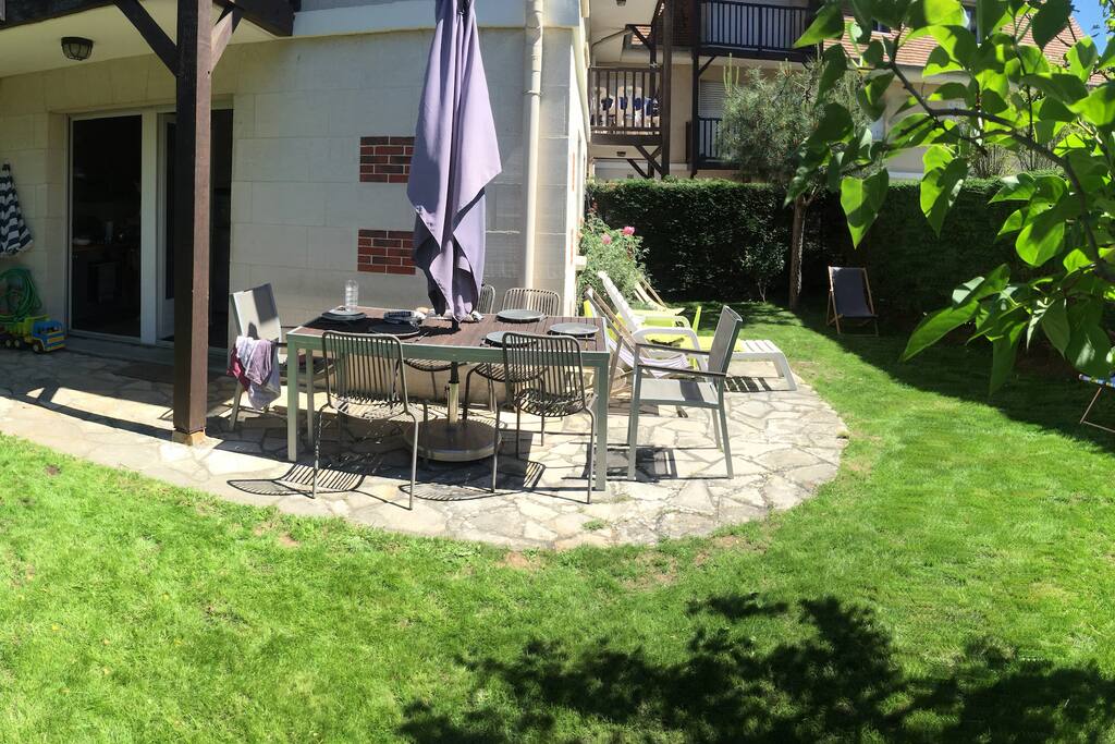 Jardin privatif avec une table permettant des repas à l'extérieur.