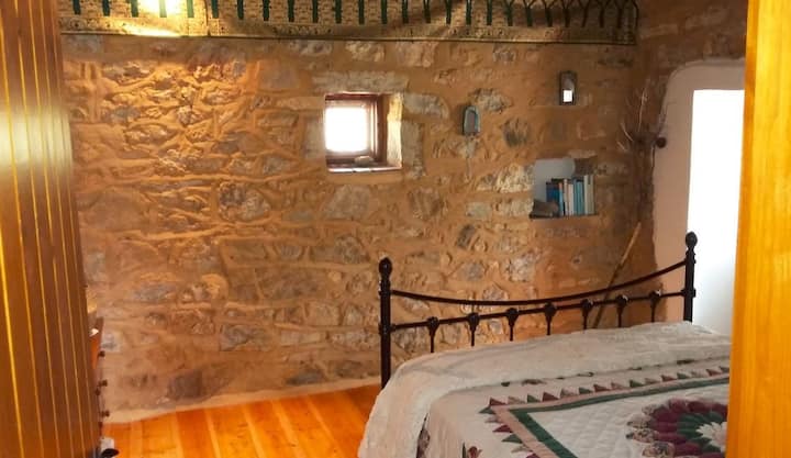 Glavna spavaća soba s bračnim krevetom. Teška drvena vrata otvaraju se na bočnu stranu kuće s bijelim Bougainvilleom koji raste iznad glave.