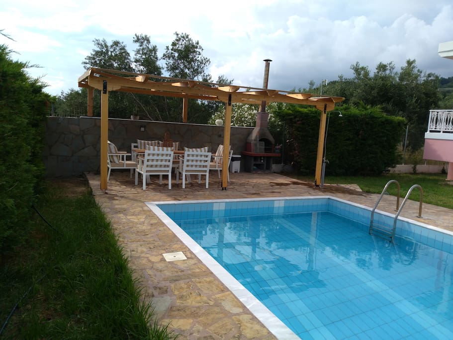 A wooden gazebo with two seater sofa, four chairs and barbeque facilities.