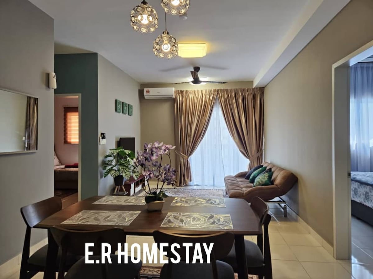 A dining area is featured with a wooden table set for four, surrounded by chairs. A cozy seating arrangement is observed in the background, with large windows draped in curtains allowing natural light to filter through. Decorative plants and light fixtures add a modern touch.
