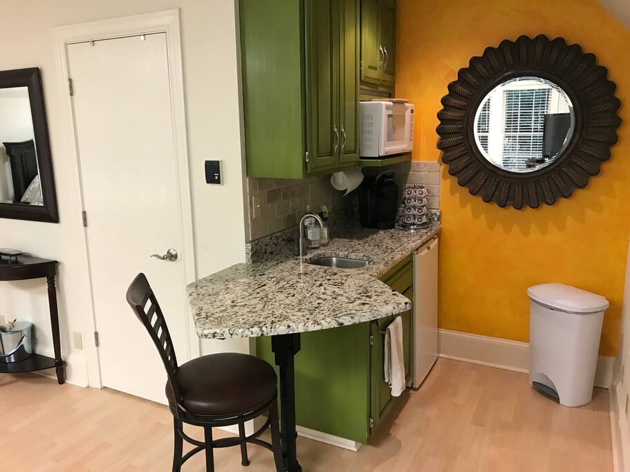 Kitchenette with counter seating, microwave, sink and fridge.