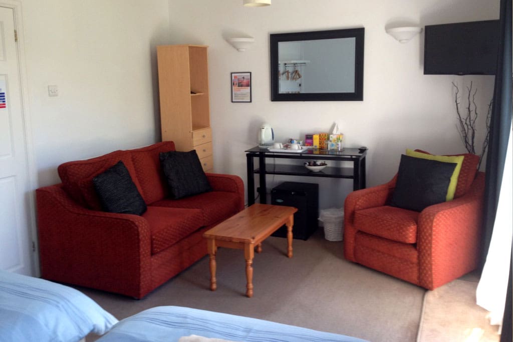 Lovely lounge area in room, with sofa, chair and TV. Kettle, with coffee and tea, and mini-fridge in room.