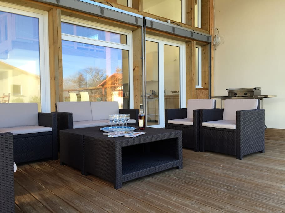 Terrasse équipée d'un salon de jardin et d'une plancha