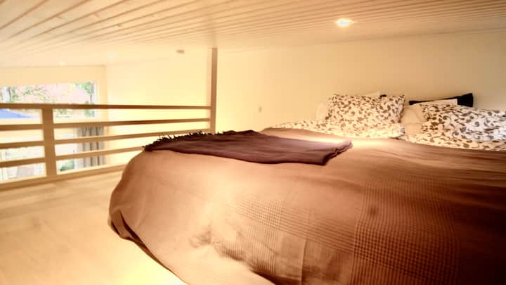 Gran loft para dormir con una cama cómoda, de 180 cm de ancho. Pequeña ventana junto a la cama que se puede abrir.