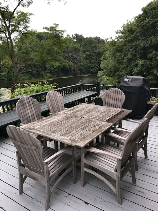 Gas BBQ and outdoor table on large deck overlooking river next to kitchen